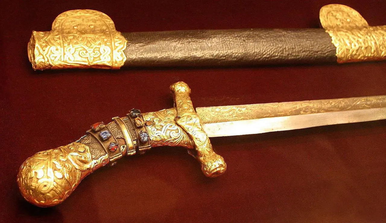 Altın kabzalı, hafif kavisli bir sabre ve üstünde kını. Kabza ve balçak kabartma altın işlemeli, kabza bileziğinde kırmızı ve mavi taşlar kakılı.