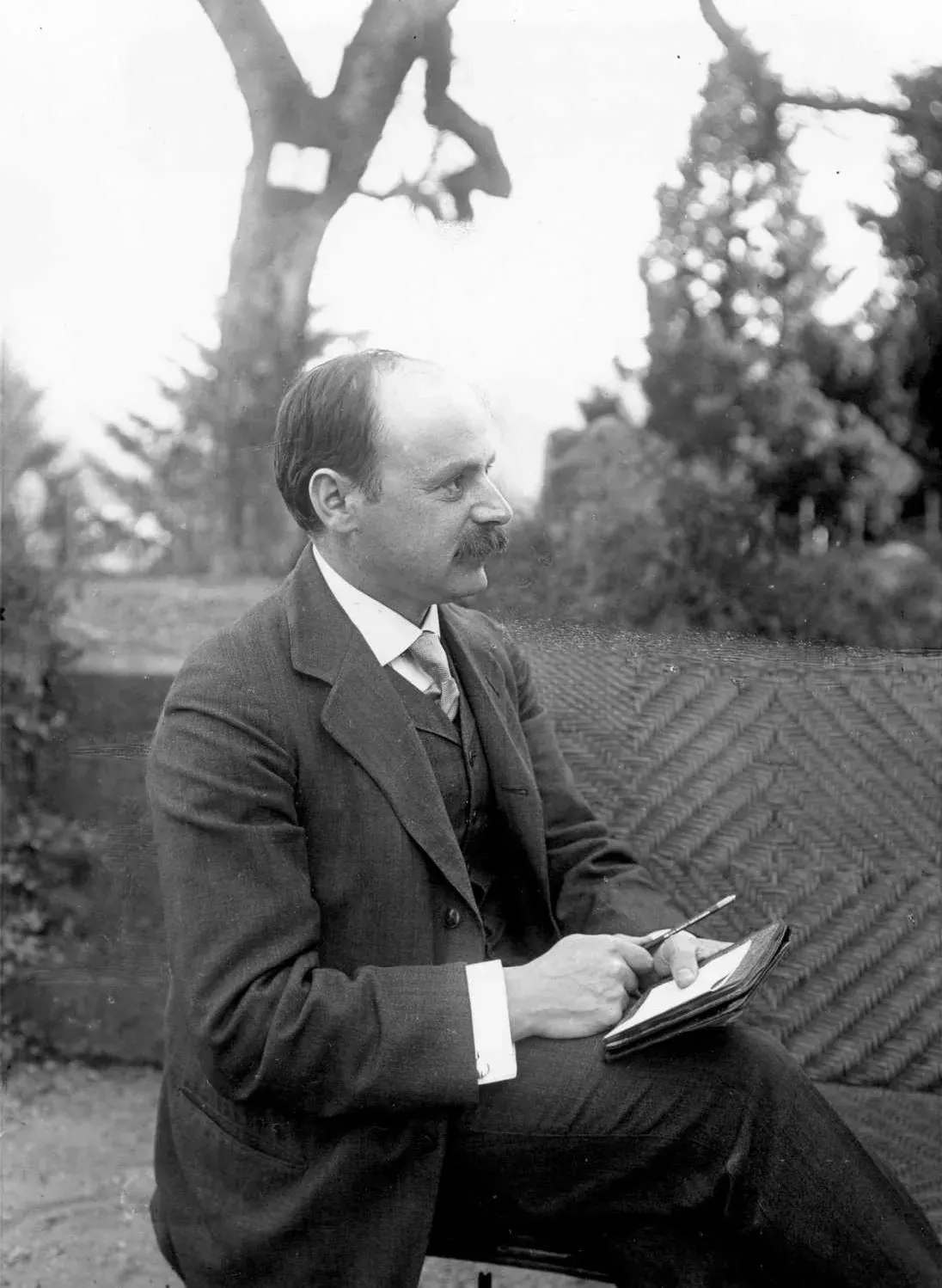 Bıyıklı, takım elbiseli bir adamın 20. yüzyıl başı siyah beyaz portresi.
