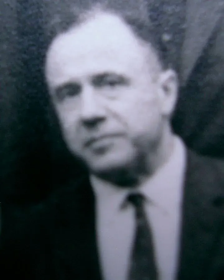 Takım elbiseli, gözlüklü bir adamın 1960'lar siyah beyaz portresi.