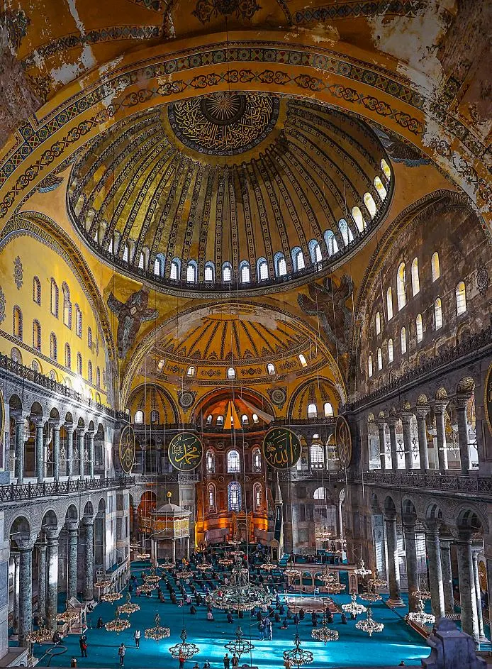 Ayasofya kubbesinin içi: dev hat levhaları, avizeler, mavi halı.