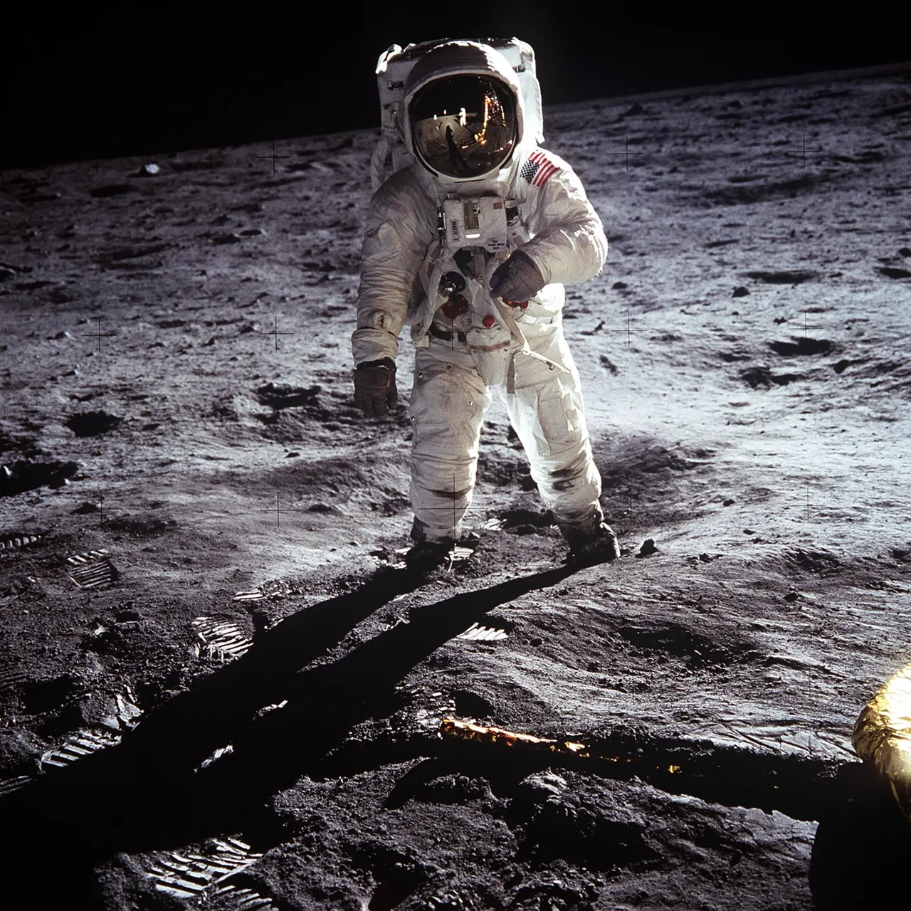 Ay yüzeyinde beyaz uzay giysili bir astronot; arkada siyah gökyüzü ve gri, tozlu zemin.
