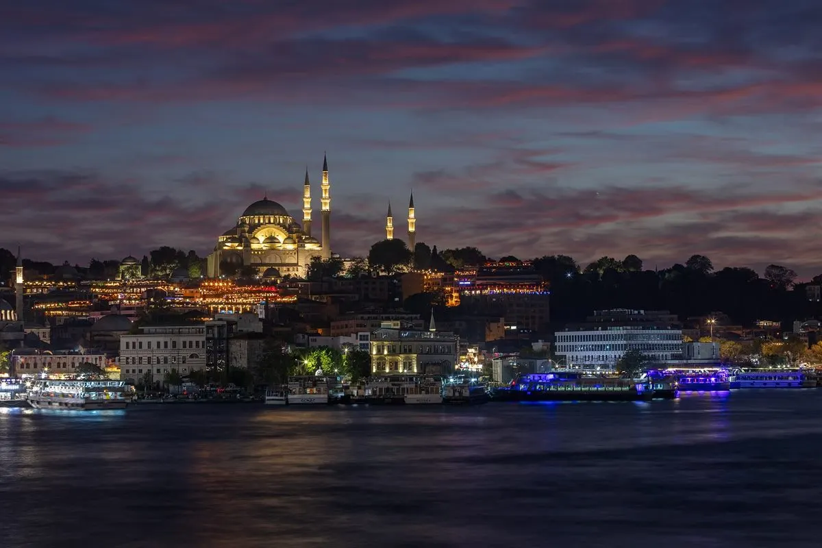 Alacakaranlıkta Haliç'ten Süleymaniye: aydınlatılmış kubbe ve dört minare, altta sahil, ışıklı vapurlar ve su.