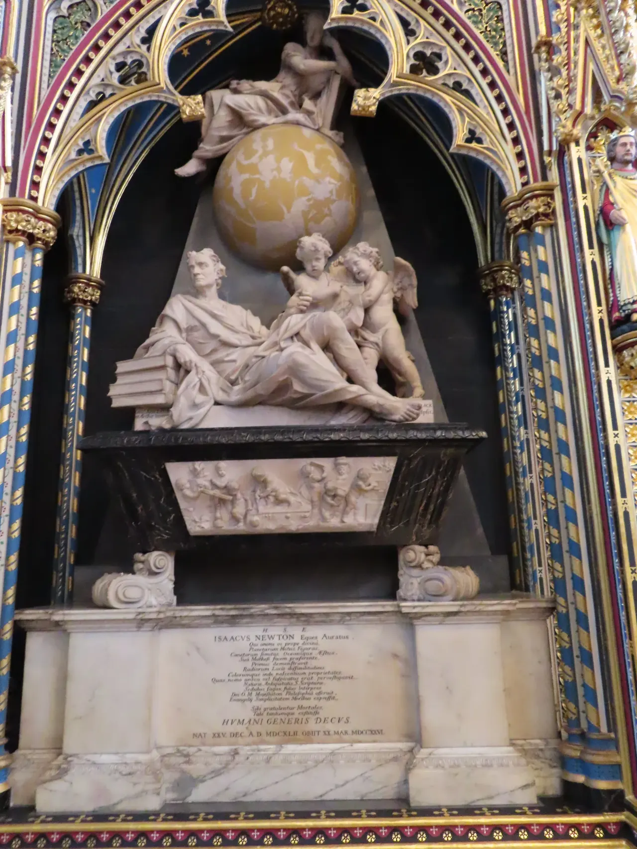 Kilise içindeki görkemli mermer anıt: yarı uzanmış bir figür, çevresinde melek figürleri ve gök küresi kabartması.